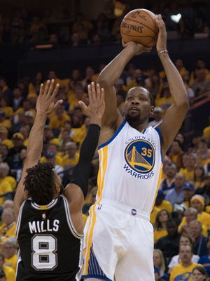Golden State Warriors forward Kevin Durant shoots the basketball against San Antonio Spurs guard Patty Mills during the second quarter in Game 1 of the Western Conference finals.