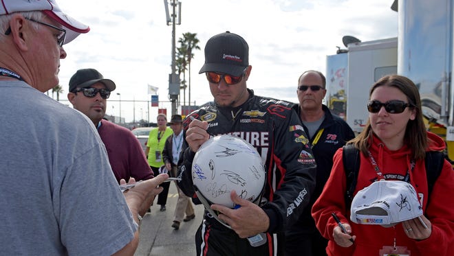 Martin Truex Jr, center, signs autographs before practice for the 2015 Daytona 500.
