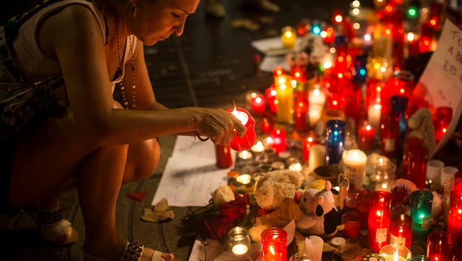 A woman lights up a candle at a memorial tribute to the victims of the vehicle attacks on Barcelona's historic Las Ramblas promenade, in Barcelona, Spain on Aug. 20, 2017.