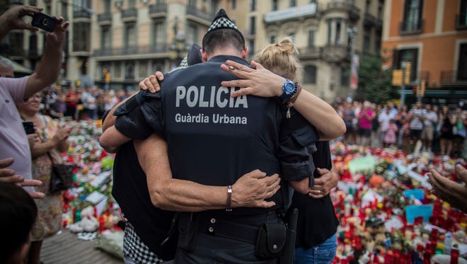 A policeman hugs a boy and his family that he helped during the terrorist attack, at a memorial to the victims on Las Ramblas, Barcelona, Spain on Aug. 21, 2017.