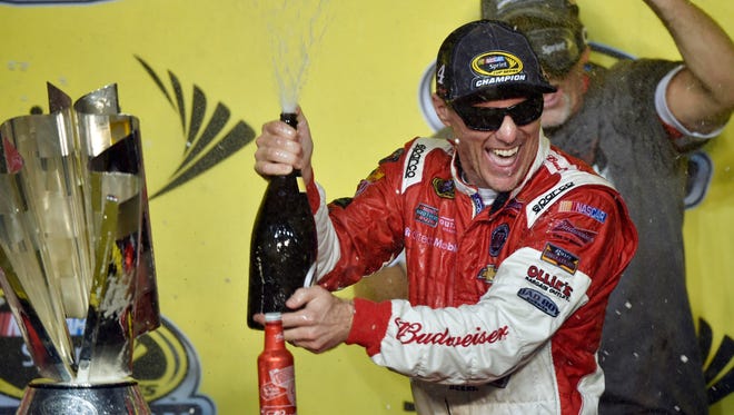 Kevin Harvick celebrates with a bottle of champagne, a bottle of Budweiser and the championship trophy after earning his first NASCAR Sprint Cup championship on Nov. 16, 2014.