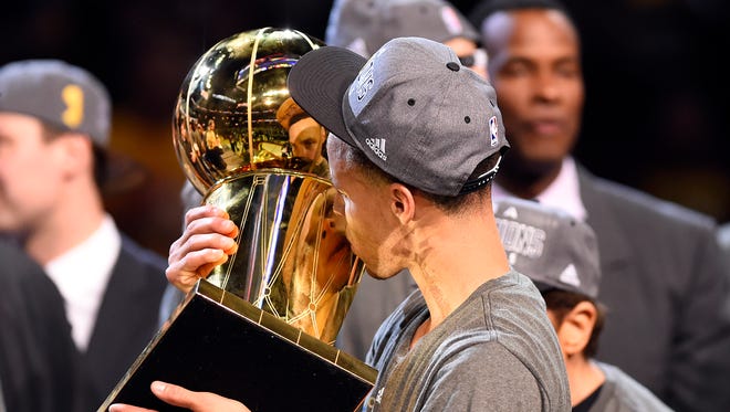 2015: Stephen Curry kisses the Larry O'Brien Trophy after beating the Cleveland Cavaliers in Game 6 of the NBA Finals.