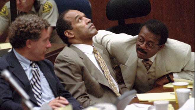 Simpson stares at the ceiling as defense attorneys Johnnie Cochran Jr., right, and Peter Neufeld confer during the trial in 1995.