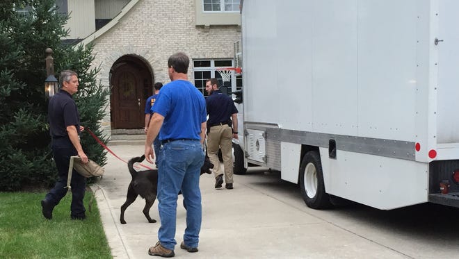 U.S. Postal Inspection Police enter the home of Subway spokesman Jared Fogle with a police dog on Tuesday morning, July 7, 2015, during a criminal investigation being conducted by the Indiana State Police and FBI at Fogle's Zionsville home, where an evidence truck sits in the driveway.