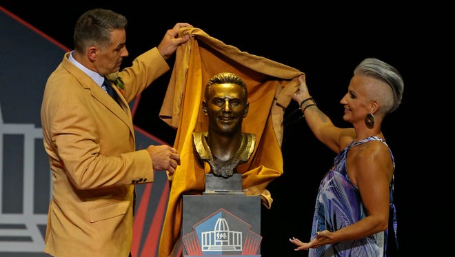 Kurt Warner pulls back the cloth on his bust with wife Brenda Warner (right) during the 2017 NFL Hall of Fame enshrinement at Tom Benson Hall of Fame Stadium.