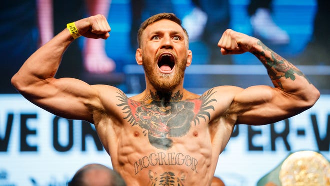 Conor McGregor flexes as he stands on the scale during weigh-ins for his upcoming boxing match at T-Mobile Arena.