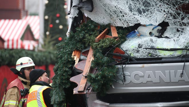 A police officer and firefighter inspect a damaged truck on a road beside the Christmas market in Berlin, Germany on Dec. 20, 2016.