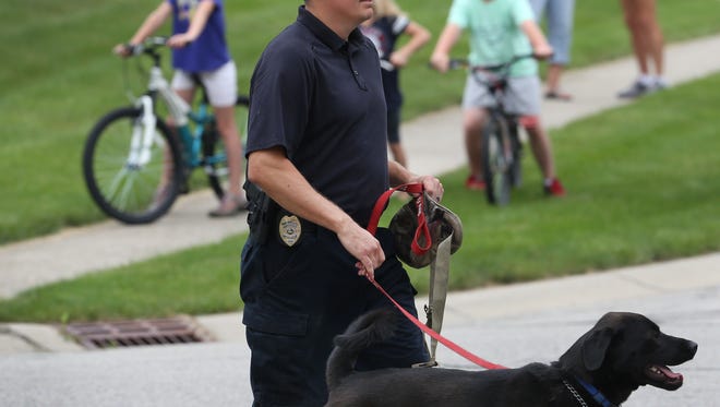 A fire marshall from Anderson, Ind. walks a police dog up to the Zionsville home of Subway spokesperson Jared Fogle in the 4500 block of Woods Edge Drive in the Austin Oaks subdivision where law enforcement, including the FBI, Indiana State Police and U.S. Postal Inspection Policeconducted a morning-long investigation at Fogle's home on Tuesday morning, July 7, 2015.