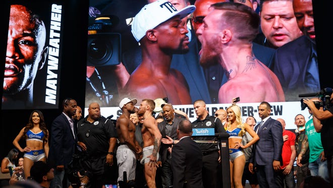 Floyd Mayweather (left) faces off against Conor McGregor during weigh-ins for their upcoming boxing match at T-Mobile Arena.