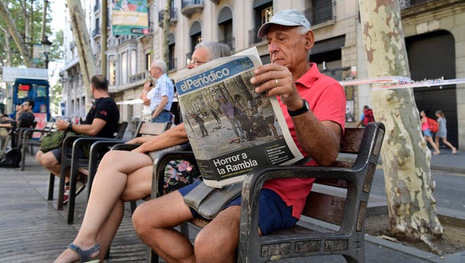 A person, on a bench of La Rambla boulevard, reads the Catalan newspaper el Periodico on Aug. 18, 2017.
