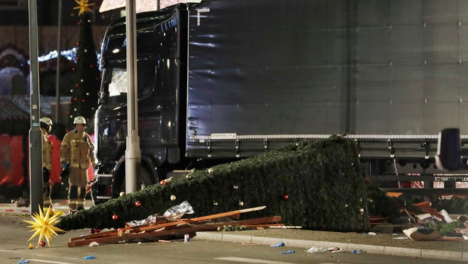 Firefighters stand beside a truck which ran into a crowded Christmas market and killed several people in Berlin, Germany, on Dec. 19, 2016.