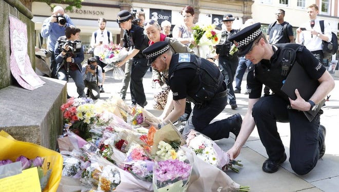 Police offices add to the flowers for the victims of Monday night pop concert explosion, in St Ann's Square, Manchester,  Tuesday May 23, 2017. A 23-year-old man was arrested in connection with Monday's Manchester concert bomb attack. The Islamic State group claimed responsibility Tuesday for the suicide attack at an Ariana Grande show that left over 20 people dead and dozens injured.