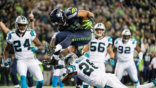 Seattle Seahawks running back Thomas Rawls (34) leaps over Carolina Panthers cornerback Daryl Worley (26) for a touchdown during the first quarter at CenturyLink Field.