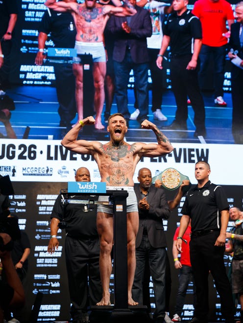 Conor McGregor flexes as he stands on the scale during weigh-ins for his boxing match against Floyd Mayweather.