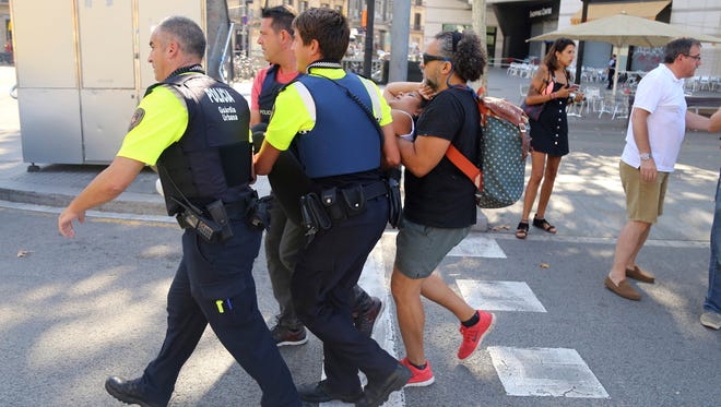 An injured person is carried in Barcelona after a white van jumped the sidewalk in the historic Las Ramblas district, crashing into a summer crowd of residents and tourists and injuring several people, police said.