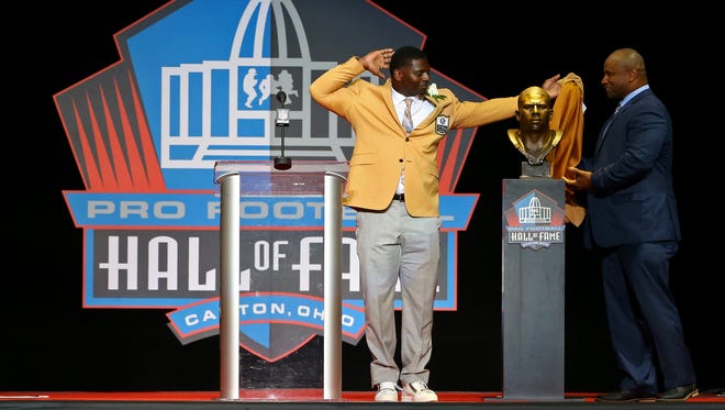 LaDainian Tomlinson pulls back the cloth on his bust with Lorenzo Neal (right) during the 2017 Pro Football Hall of Fame enshrinement at Tom Benson Hall of Fame Stadium.