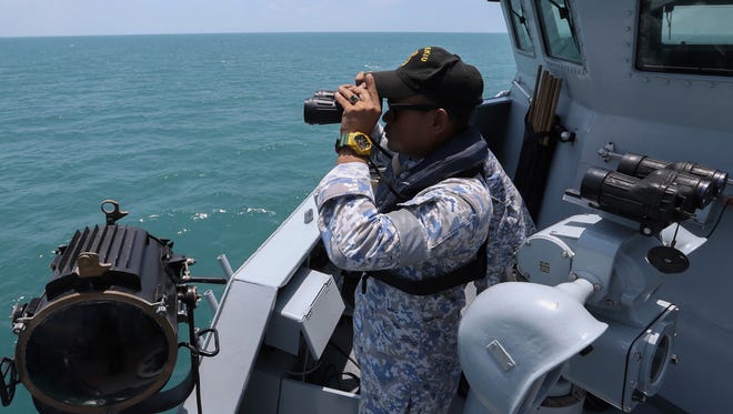 A member of the Royal Malaysian Navy uses a pair of binoculars to scan the sea for missing sailors from the USS John S. McCain off the Johor coast in Kota Tinggi, Johor in southern Malaysia.