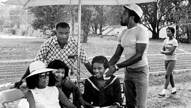The real Wilma Rudolph, left, discusses track strategy with a younger version of herself, actress Shirley Jo Finney, getting cool off by crew member, between takes of the NBC television movie, "Wilma," which began filming at St. Cecelia Academy track in Nashville July 18, 1977. The real TSU Coach Ed Temple, standing in back, listens in.