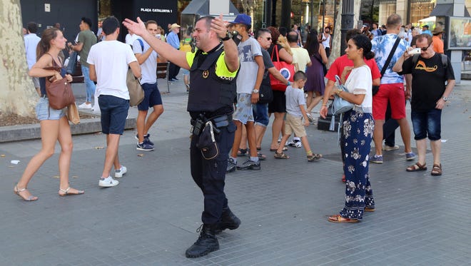 Police officers tell members of the public to leave the scene on a street in Barcelona.