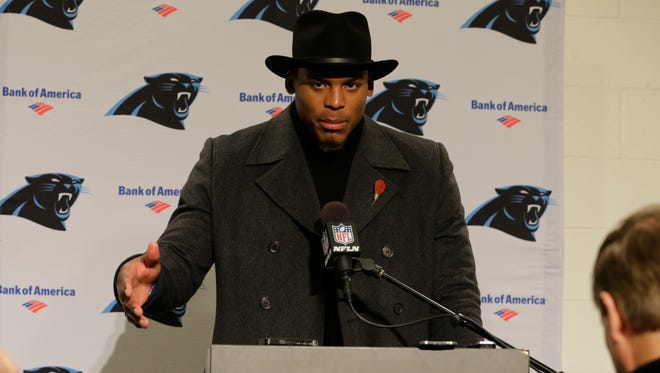 Carolina Panthers quarterback Cam Newton wears a black coat and hat as he talks with reporters during a post-game news conference after an NFL football game, Sunday, Dec. 4, 2016, in Seattle.
