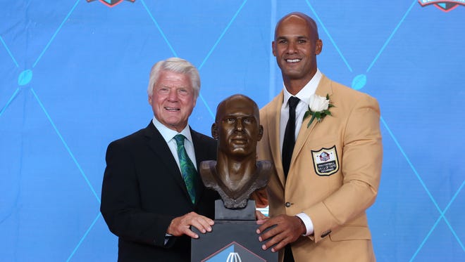 Former Miami Dolphins coach Jimmie Johnson (L) poses with former Dolphins linebacker/defensive end Jason Taylor and his bust during the Pro Football Hall of Fame enshrinement ceremonies at the Tom Benson Hall of Fame Stadium.