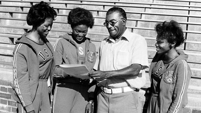 Olympic sprinter Chandra Cheeseborough, second from left, signs a grant-in-aid from Tennessee State University April 8, 1977. TSU track coach Ed Temple, second from right, holds the papers for her as Kathy McMillan, left, and Brenda Morehead, also an Olympian, look on.