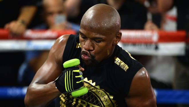 Floyd Mayweather Jr. throws punches with weights in his hands during a media workout in preparation for his fight against Conor McGregor at Mayweather Boxing Club.
