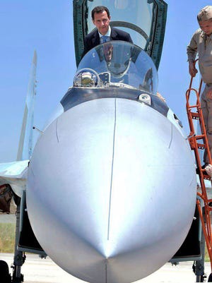 In this June 27, 2017, photo released on the official Facebook page of the Syrian Presidency, Syrian President Bashar Assad climbs into the cockpit of a Russian SU-35 fighter jet as he inspects the Russian Hmeimim air base in the province of Latakia, Syria.