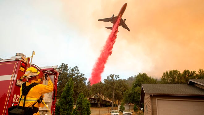 An air tanker drops fire retardant on flames as firefighters continue to battle against the Detwiler fire in Mariposa, Calif.