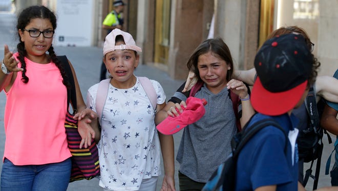 Children, some in tears, are escorted down a road in Barcelona.