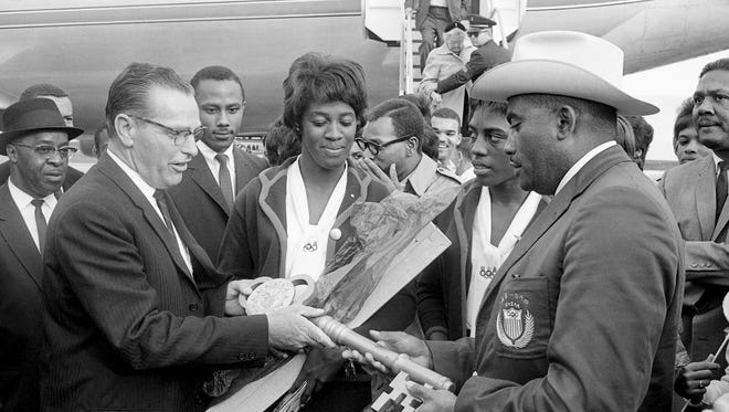 Flowers and a giant key to the city are presented to Tennessee A&I State 's Olympic heroes Edith McGuire, middle, Wyomia Tyus, second from right and Coach Ed Temple, right, by Paul Startup, left, representative of Mayor Beverly Briley, as they arrive at the Nashville Municipal Airport Oct. 28, 1964.