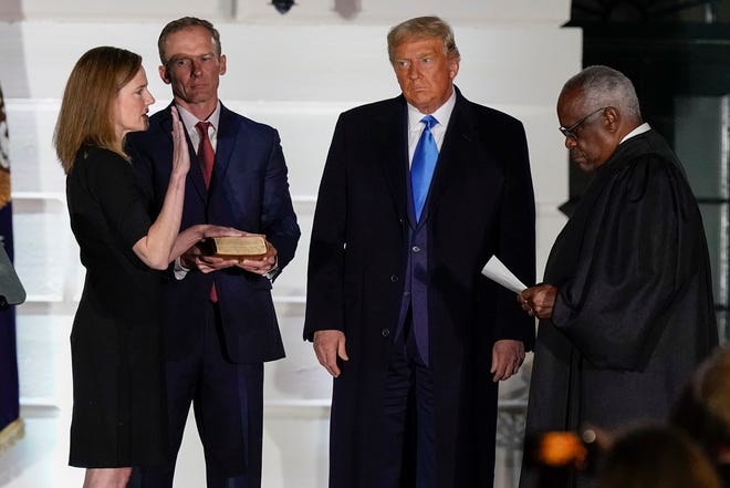 President Donald Trump watches as Supreme Court Justice Clarence Thomas administers the Constitutional Oath to Amy Coney Barrett on the South Lawn of the White House White House in Washington, Monday, Oct. 26, 2020, after Barrett was confirmed to be a Supreme Court justice by the Senate earlier in the evening. Holding the Bible is Barrett's husband, Jesse Barrett.